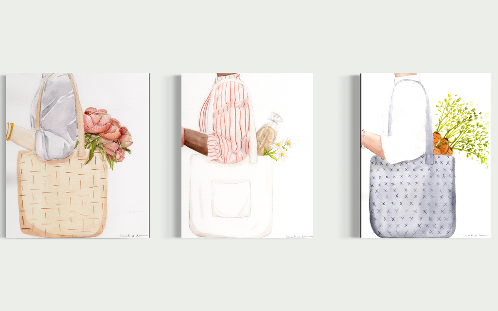 A triptych display of three minimalist watercolor paintings staged side-by-side on a neutral off-white wall. The collection, titled the Farmers Market Collection, features hand-painted illustrations of market totes with a spring aesthetic. The left panel shows a woven straw tote with coral peonies; the center panel shows a person in a red striped shirt carrying a white canvas tote with a baguette and daisies; and the right panel shows a blue textured bag with fresh carrots. The clean, modern gallery wall se